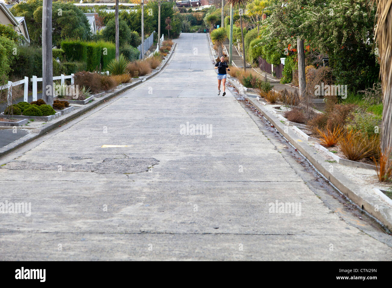Girl jogging down Baldwin Street, Dunedin, New Zealand- the steepest residential street in the world Stock Photo