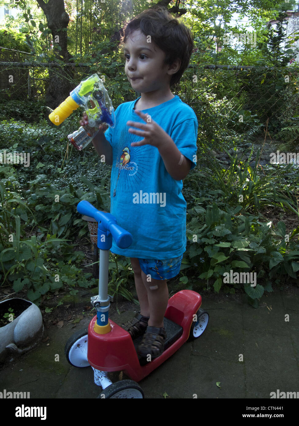 3 year old entertaining himself in the backyard, Brooklyn, NY. Stock Photo