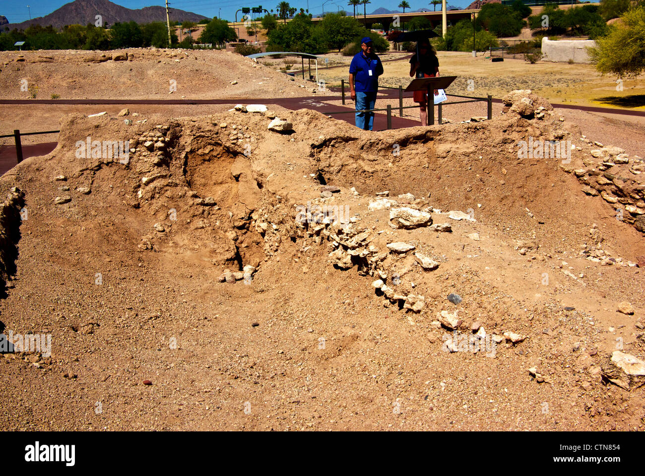 Docent showing female visitor archaeological excavation American Indian mud platform Pueblo Grande Museum outdoor exhibit Stock Photo