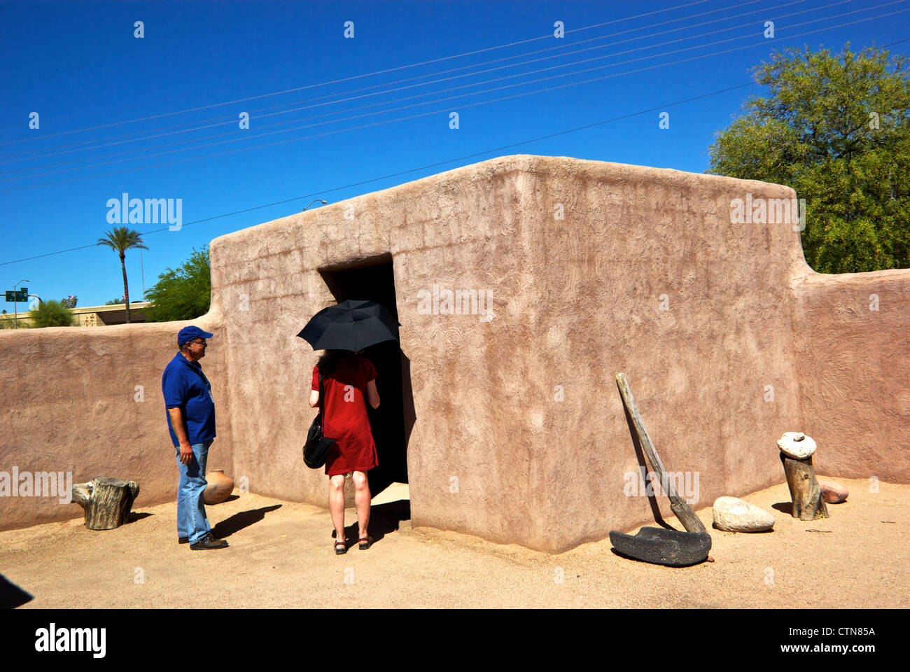Docent showing visitor archaeological recreation of Arizona First nations storage building Pueblo Grande Museum Stock Photo