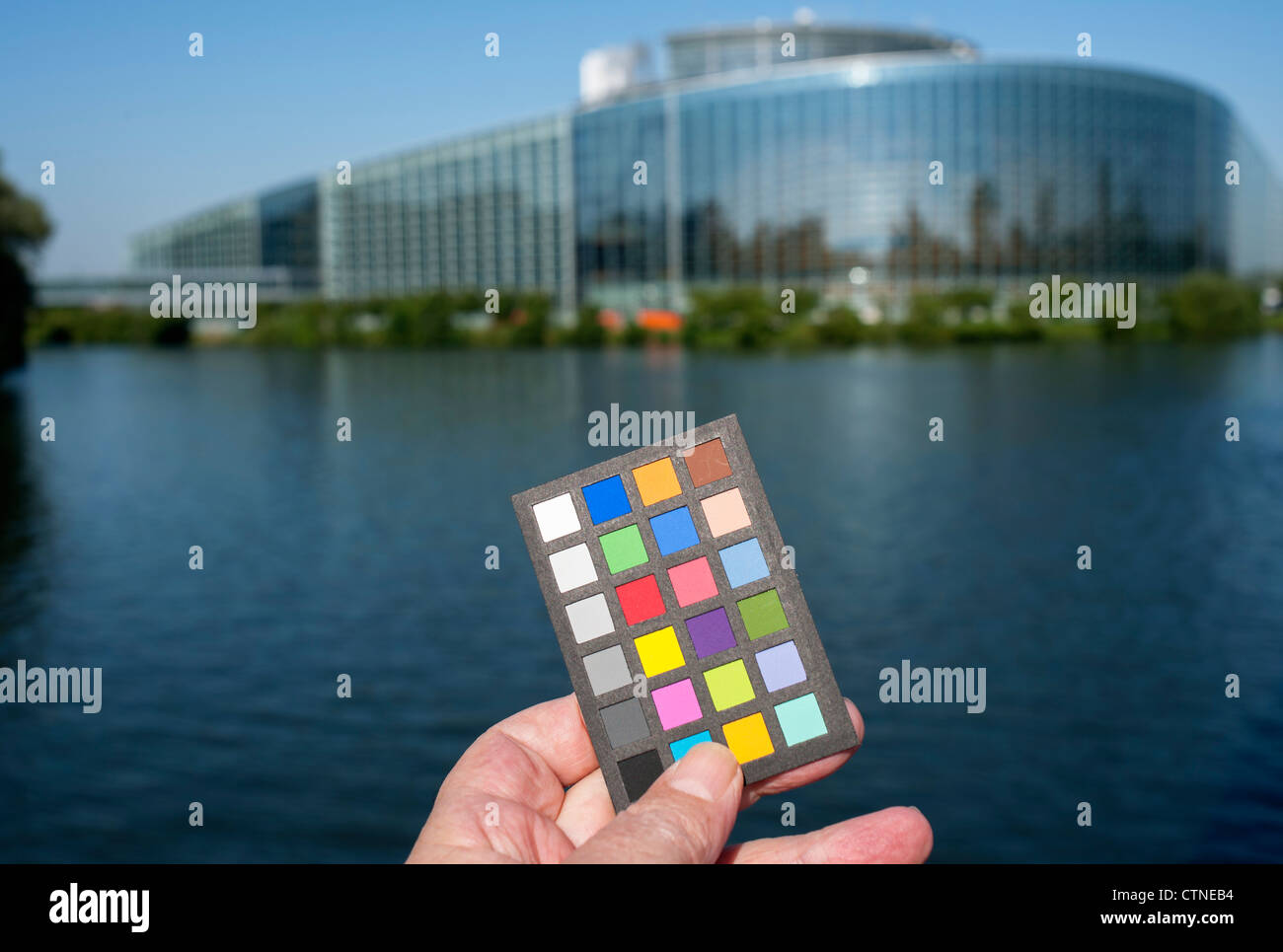 Hand holding out a Macbeth mini color checker with European Parliament building in the background, Strasbourg, Alsace, France, Europe, Stock Photo