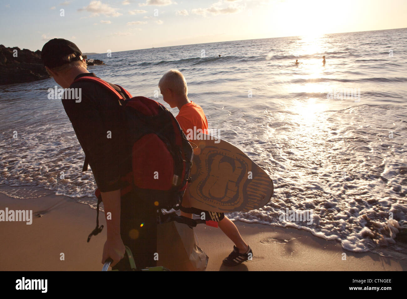 Boys carrying skimboards, Maui, Hawaii Stock Photo Alamy