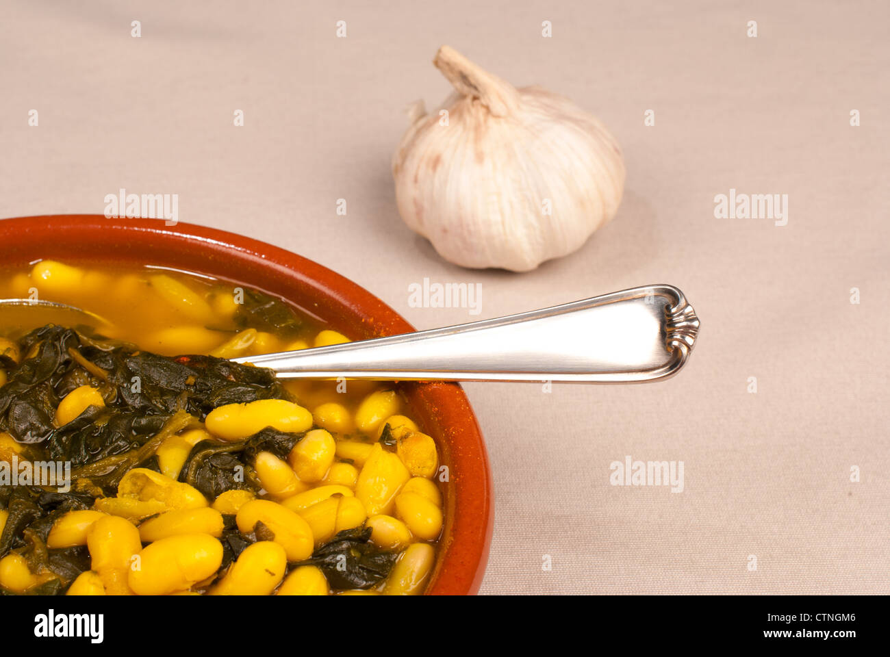 Spanish bean stew with spinach leaves served in a traditional clay pot