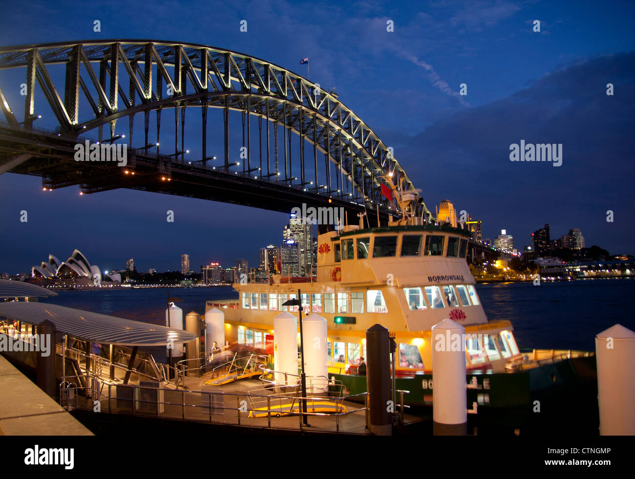Ferry at Milsons Point wharf at night with Harbour Bridge and Opera House in background Sydney New South Wales Australia Stock Photo