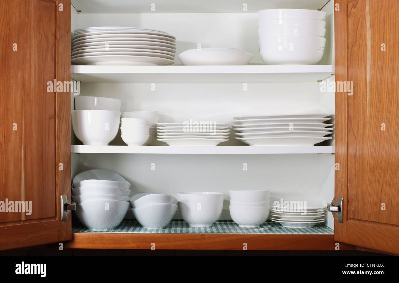 Whites dishes and bowls in oak cabinet kitchen shelf Stock Photo