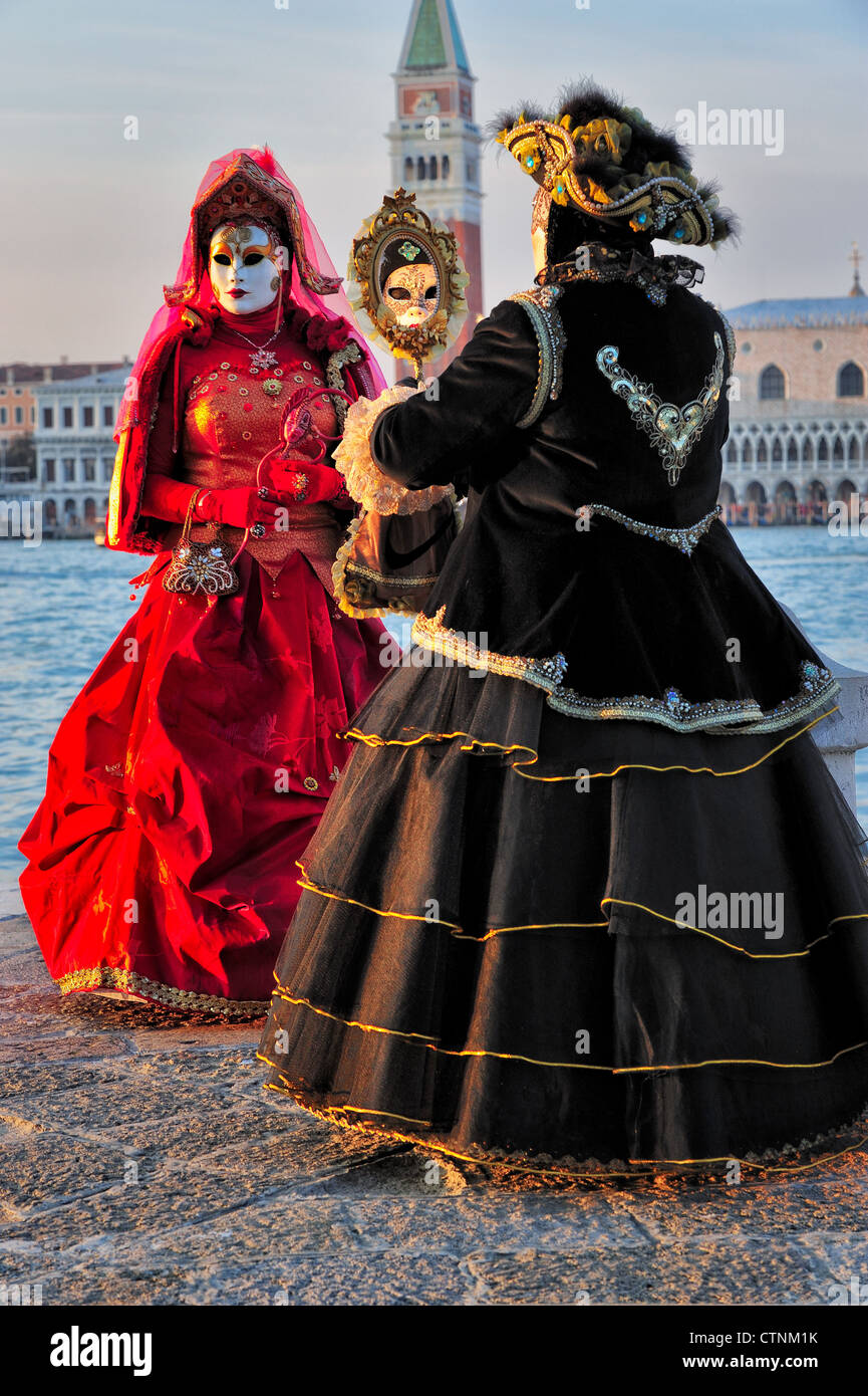 Masked participants during Carnival on San Giorgio Maggiore Island, Venice. Saint Mark's is in the background across the water. Stock Photo