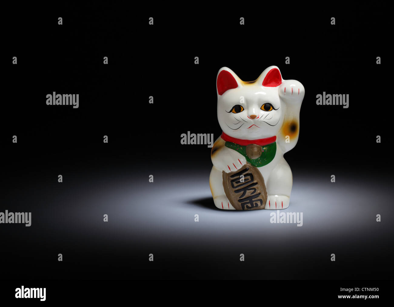 A ceramic Japanese figurine of a cat waving. Known as a Maneki-neko, Welcoming Cat, Lucky Cat, Money Cat, or Fortune Cat Stock Photo
