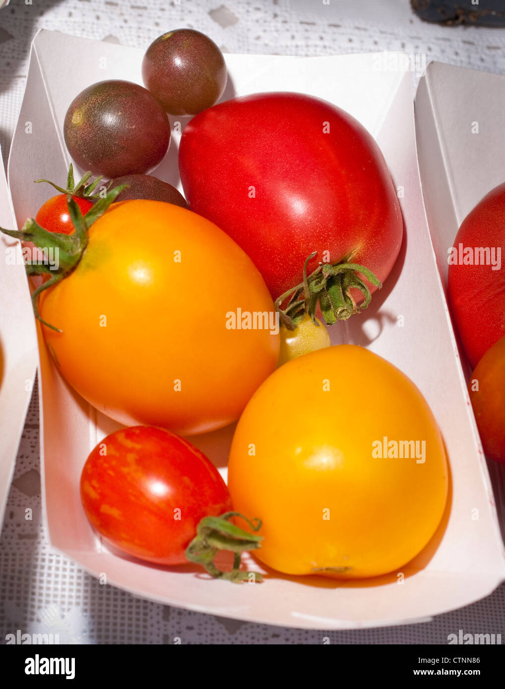 In a small paper tray tomatoes are on display for sale Stock Photo - Alamy