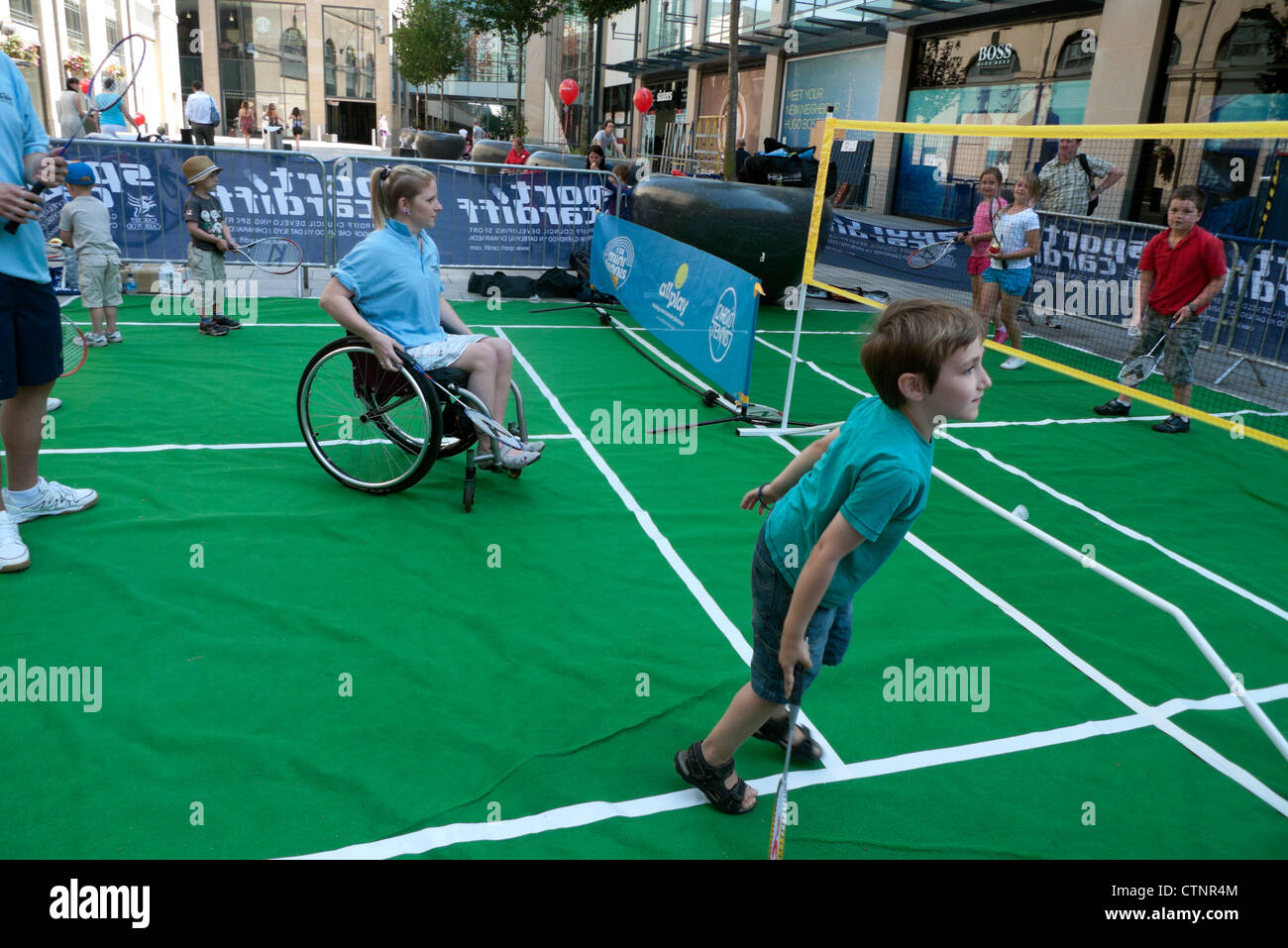 Boy and girl in wheelchair play tennis & badminton at Cardiff City ON YOUR MARKS sporting events in city centre London Olympics 2012  KATHY DEWITT Stock Photo