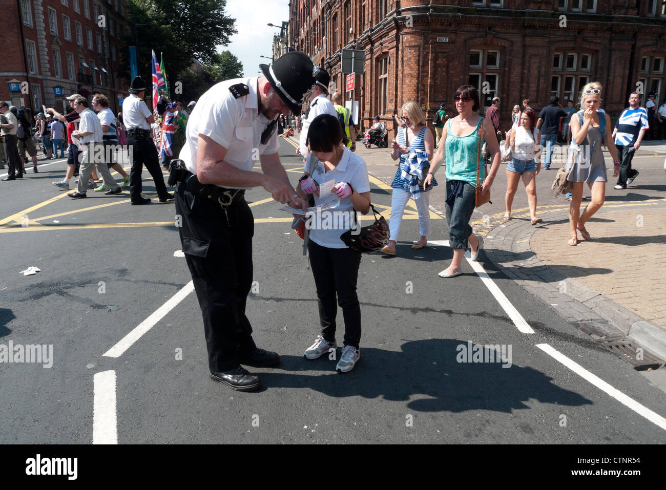 A police officer helping an Asian child tourist person in Cardiff City Centre Wales on the opening day of the 2012 London Olympics UK KATHY DEWITT Stock Photo