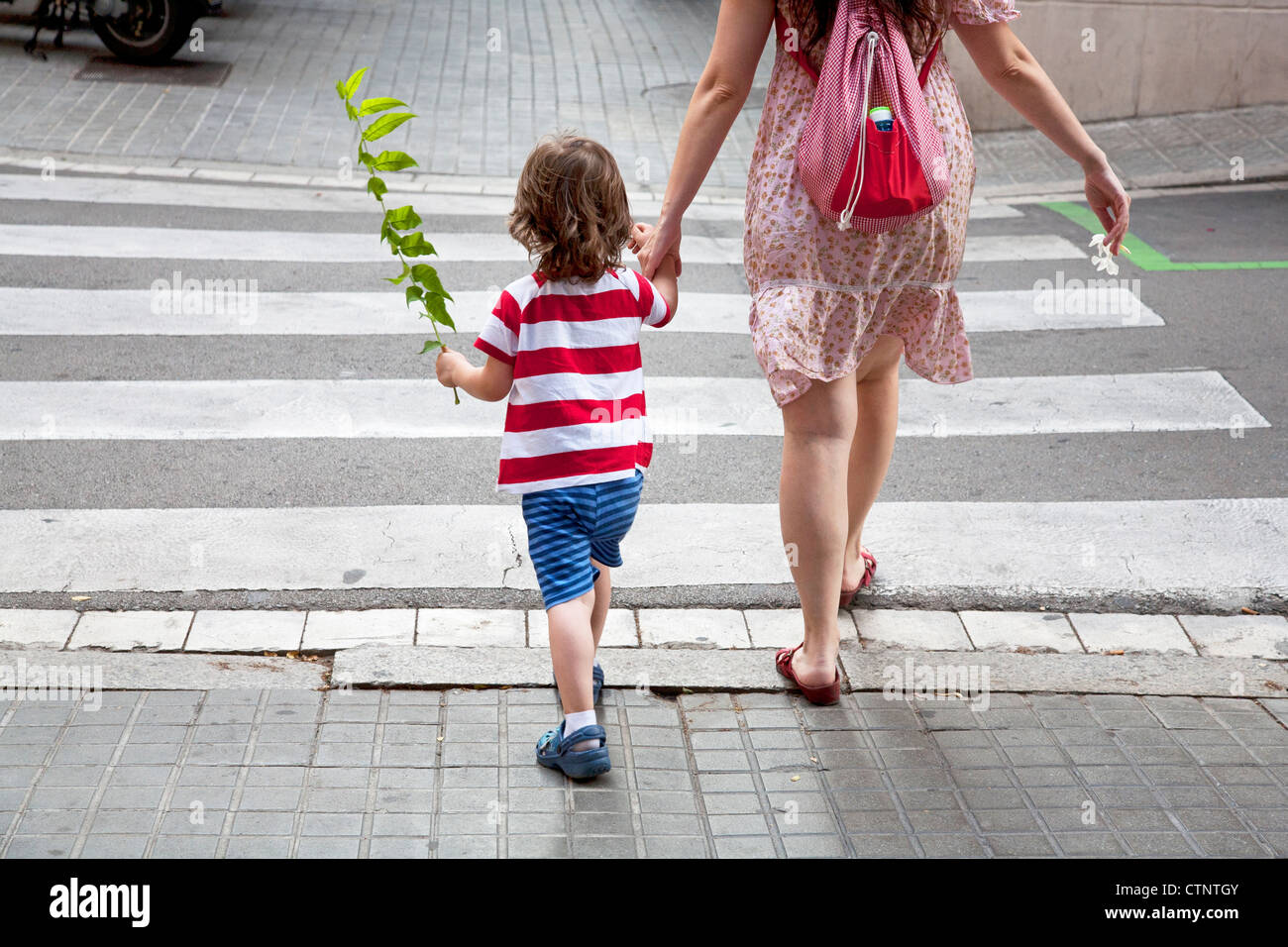 Mother and young son crossing road hand in hand Stock Photo