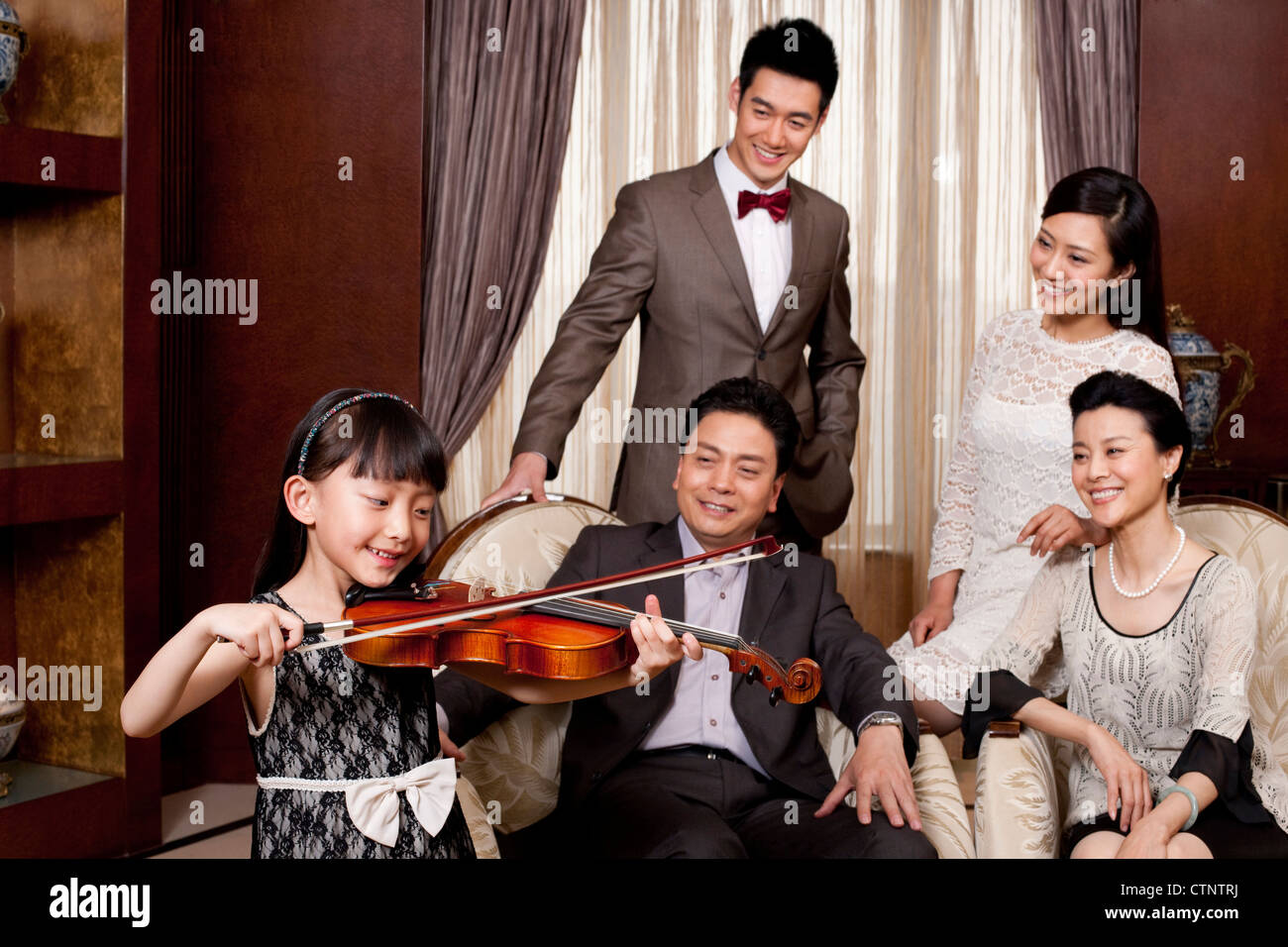 Little girl playing violin in front of family members Stock Photo - Alamy