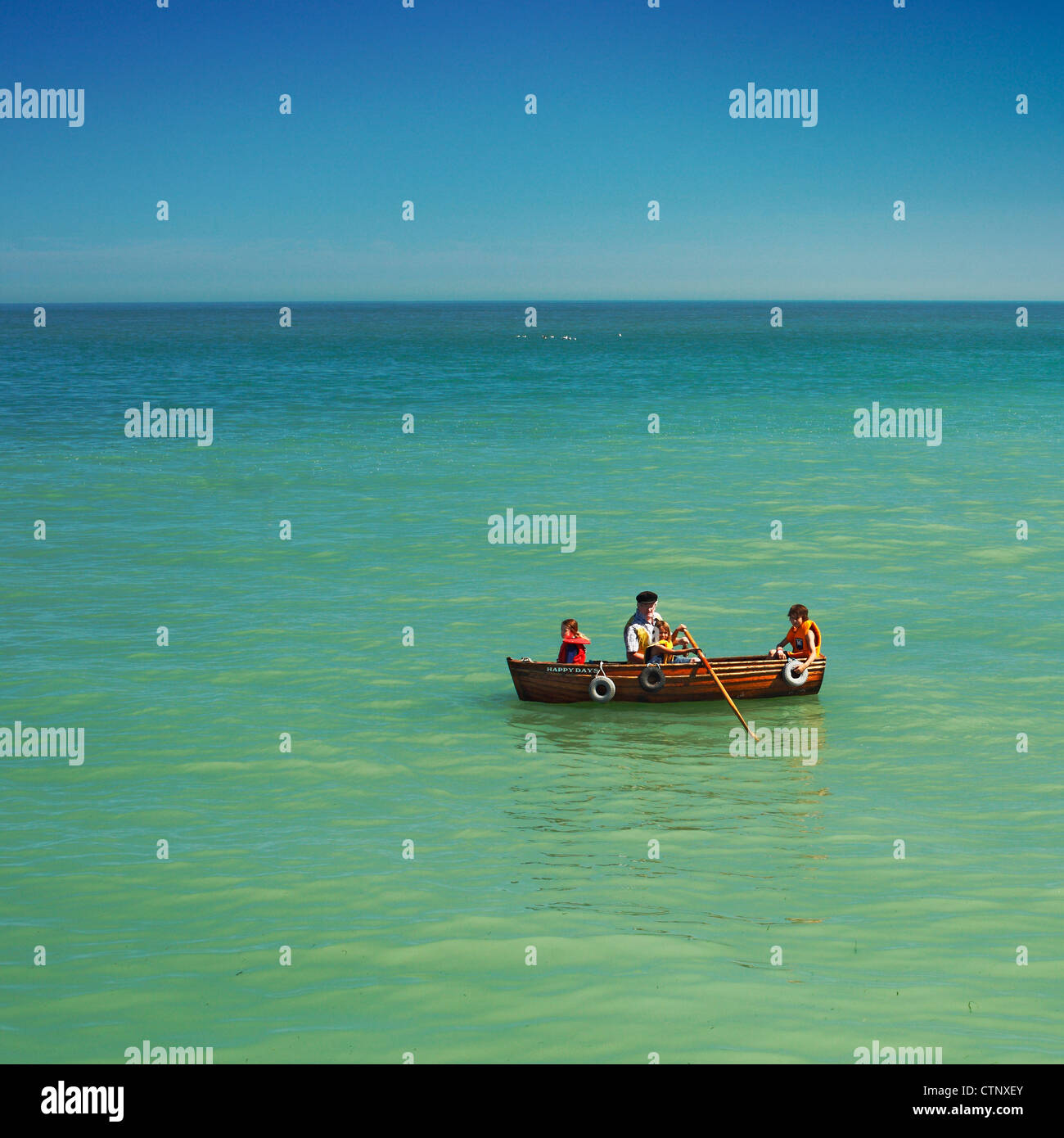 Children and senior man in a rowing boat called Happy Days . Stock Photo