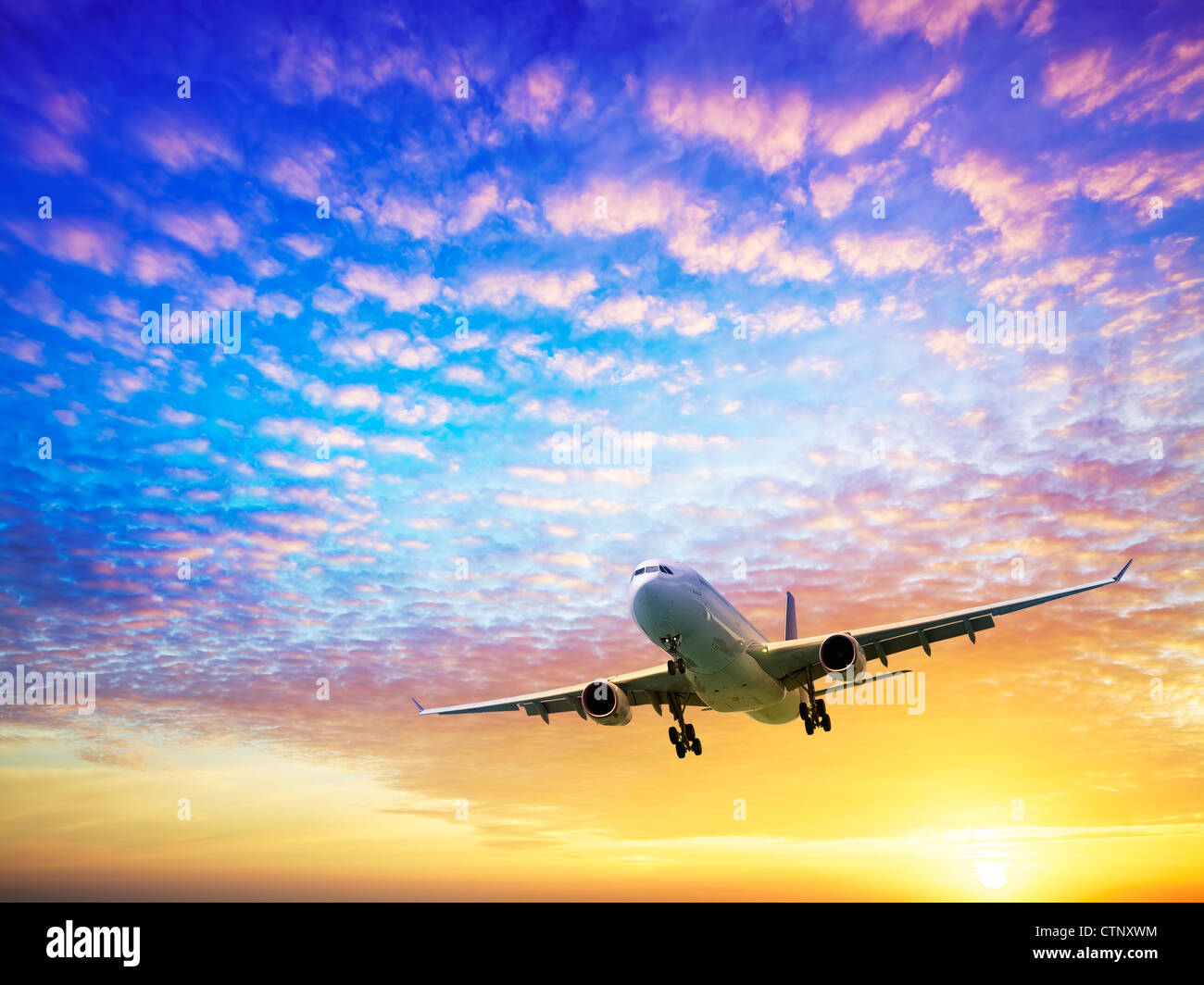 Jet plane in a sky at sunset time Stock Photo