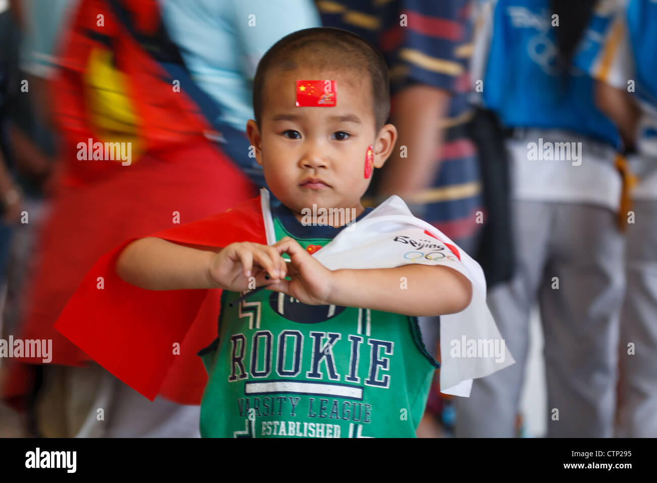 BEIJING, CHINA - AUGUST 22, 2008: young Chinese boy waving Chinese and Olympic flags in Olympic Village during the Summer Games Stock Photo