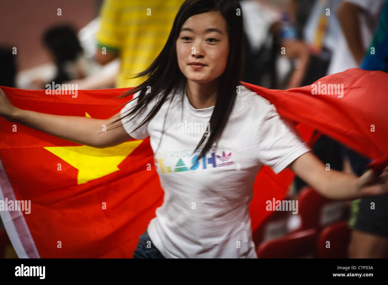 BEIJING, CHINA - AUGUST 18, 2008: Female spectator celebrates Summer Games by waving big Chinese Flag in Birds Nest Stadium Stock Photo