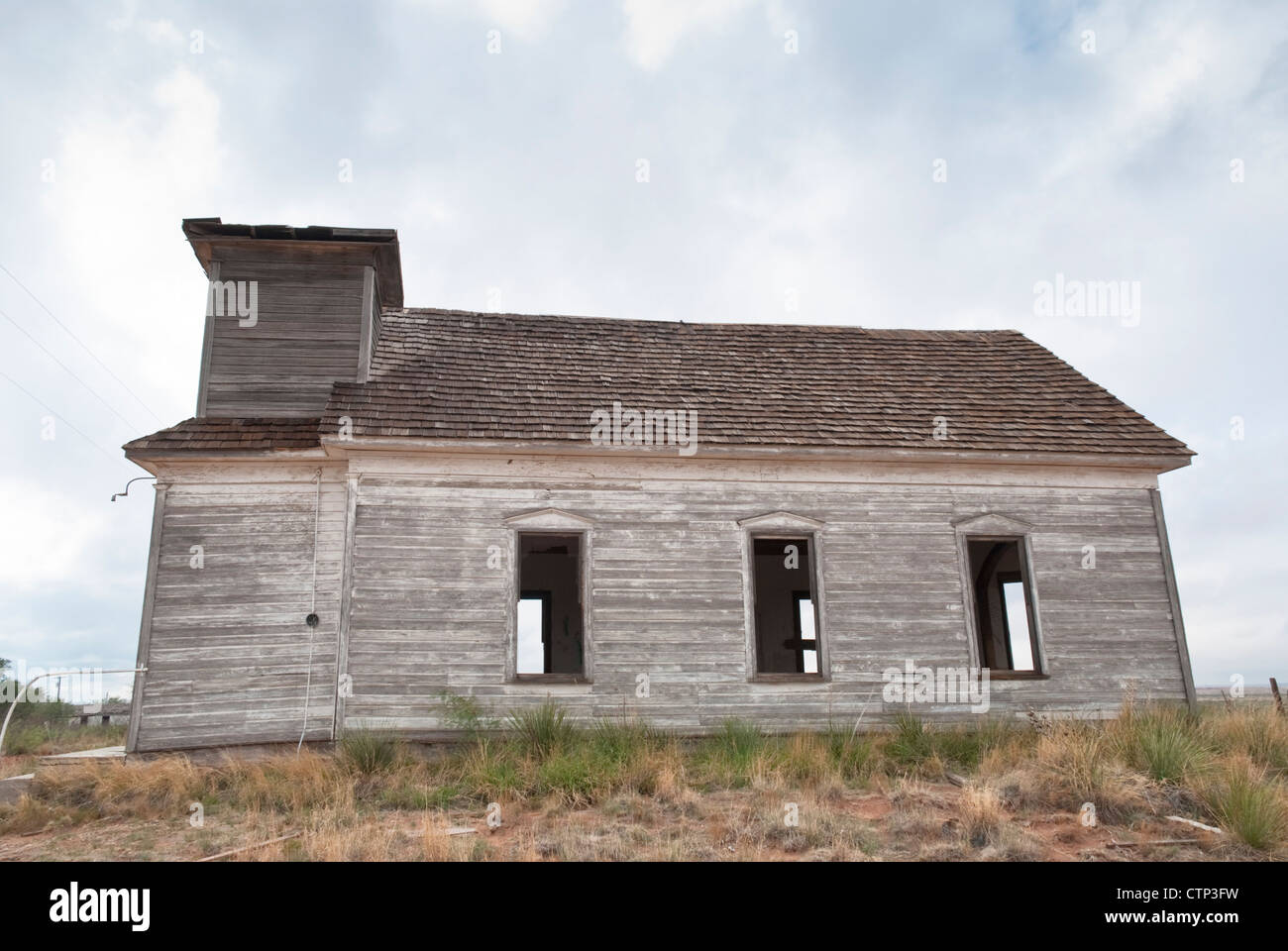 A short side road in the mostly uninhabited rural town of Taiban, New Mexico reveals an abandoned school house. Stock Photo