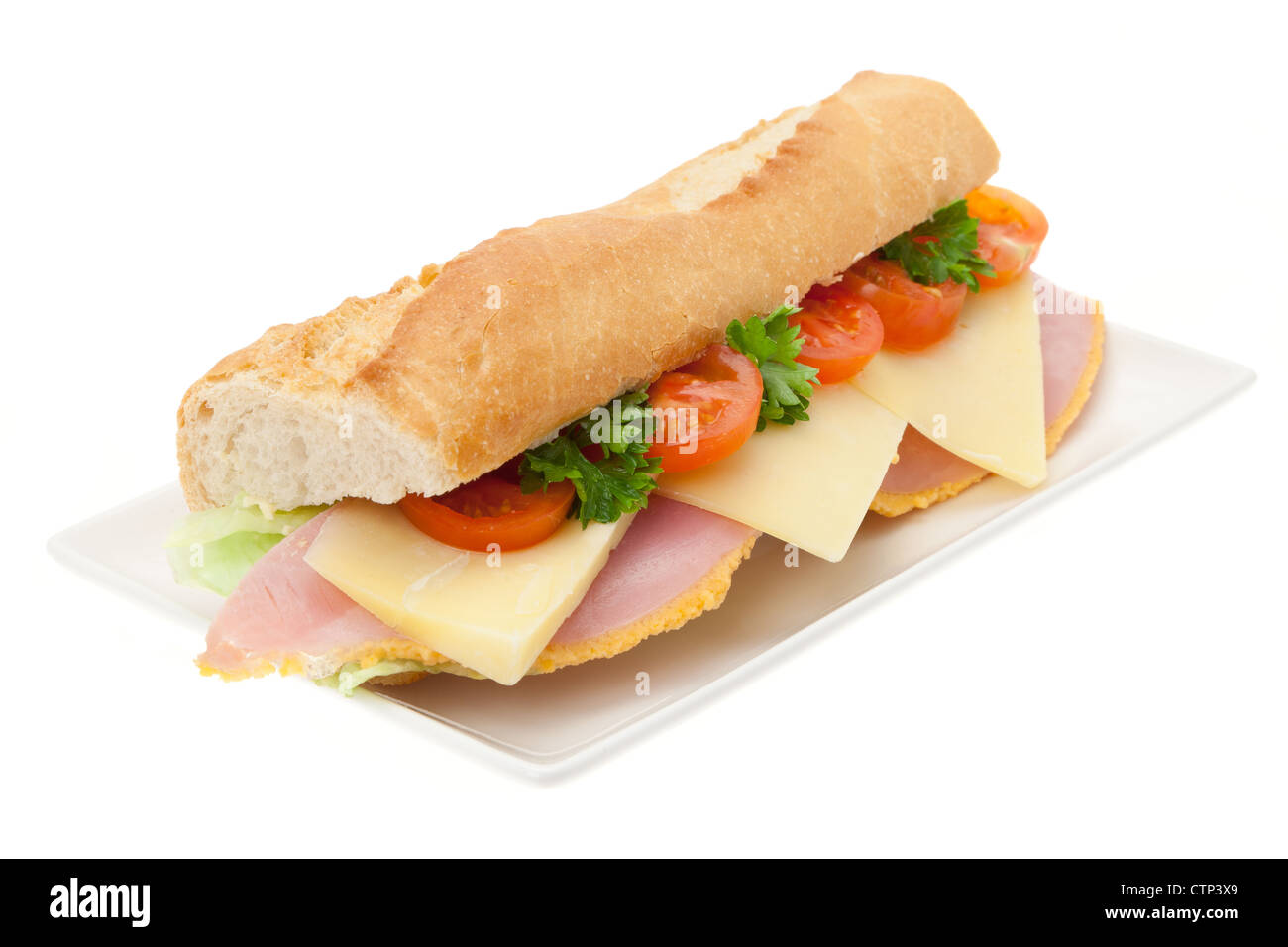 A fresh ham, cheese and salad sandwich in a French baguette on a white china plate - studio shot with a white background Stock Photo
