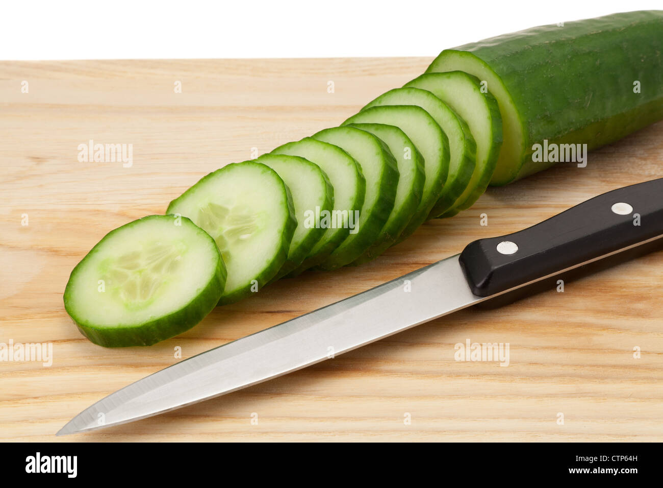 Sliced cucumber on a wooden cutting board with a kitchen knife - studio shot Stock Photo