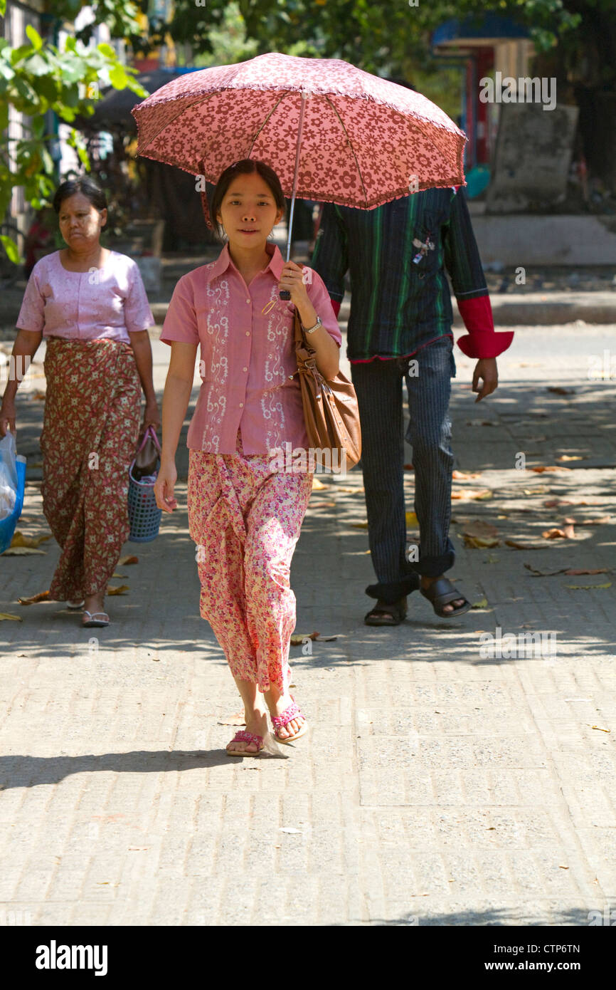 Burmese woman walking under the shade of an umbrella in (Rangoon) Yangon, (Burma) Myanmar. Stock Photo