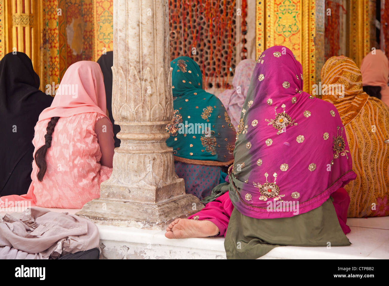 Muslim women wearing colourful headscarfs and saris praying at the Nizam-Ud-Din shrine in Delhi, India Stock Photo