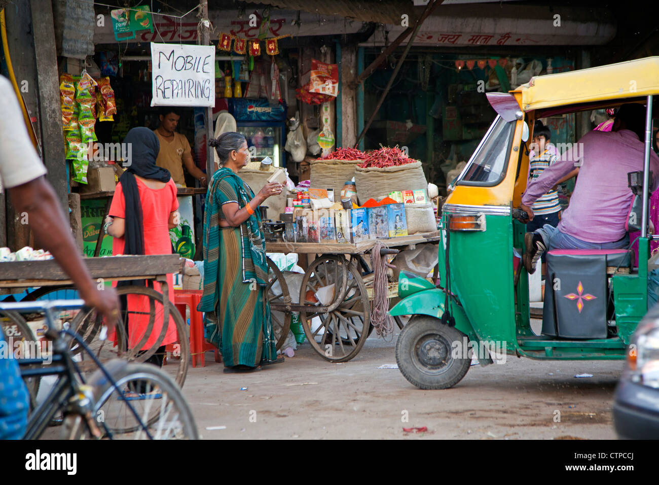 Mobile repair shop and three-wheeled taxi / bajaj in busy street in Delhi, India Stock Photo