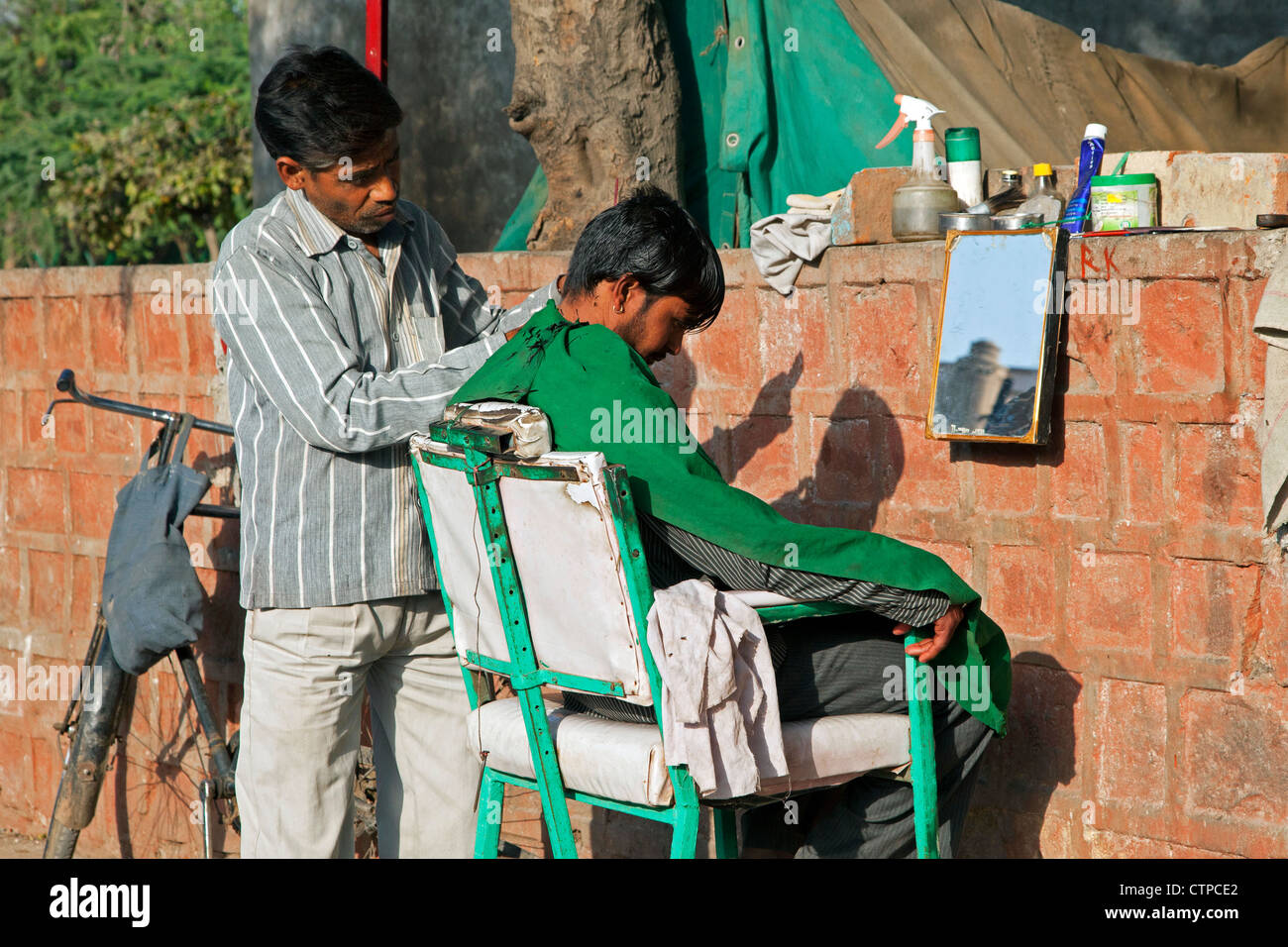 Hairdresser cutting boy's hair in the streets of Agra, Uttar Pradesh, India Stock Photo