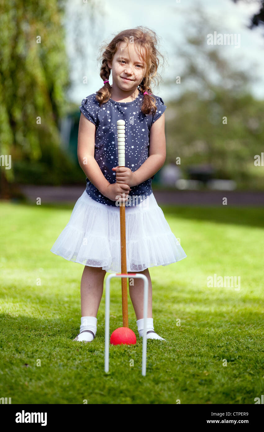 young caucasian girl aged 5 playing croquet in her garden; UK Stock Photo Alamy