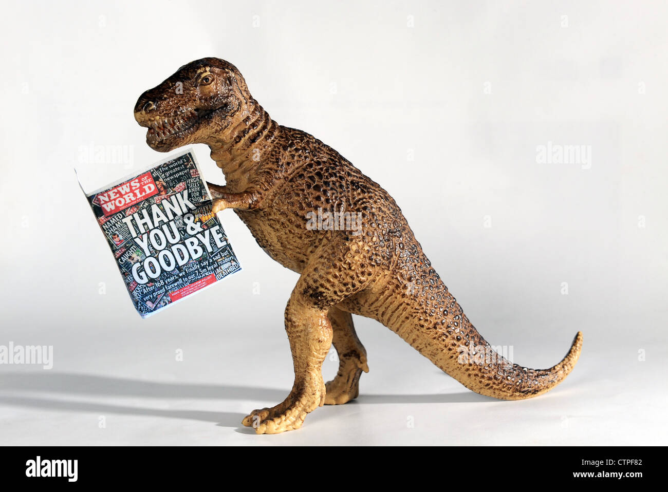 News of the World newspaper held by toy dinosaur Stock Photo