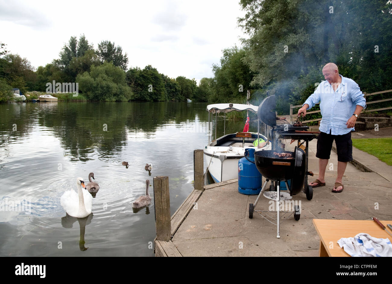 Man doing a barbecue bbq on the river bank, the River Thames at Wallingford Oxfordshire UK Stock Photo