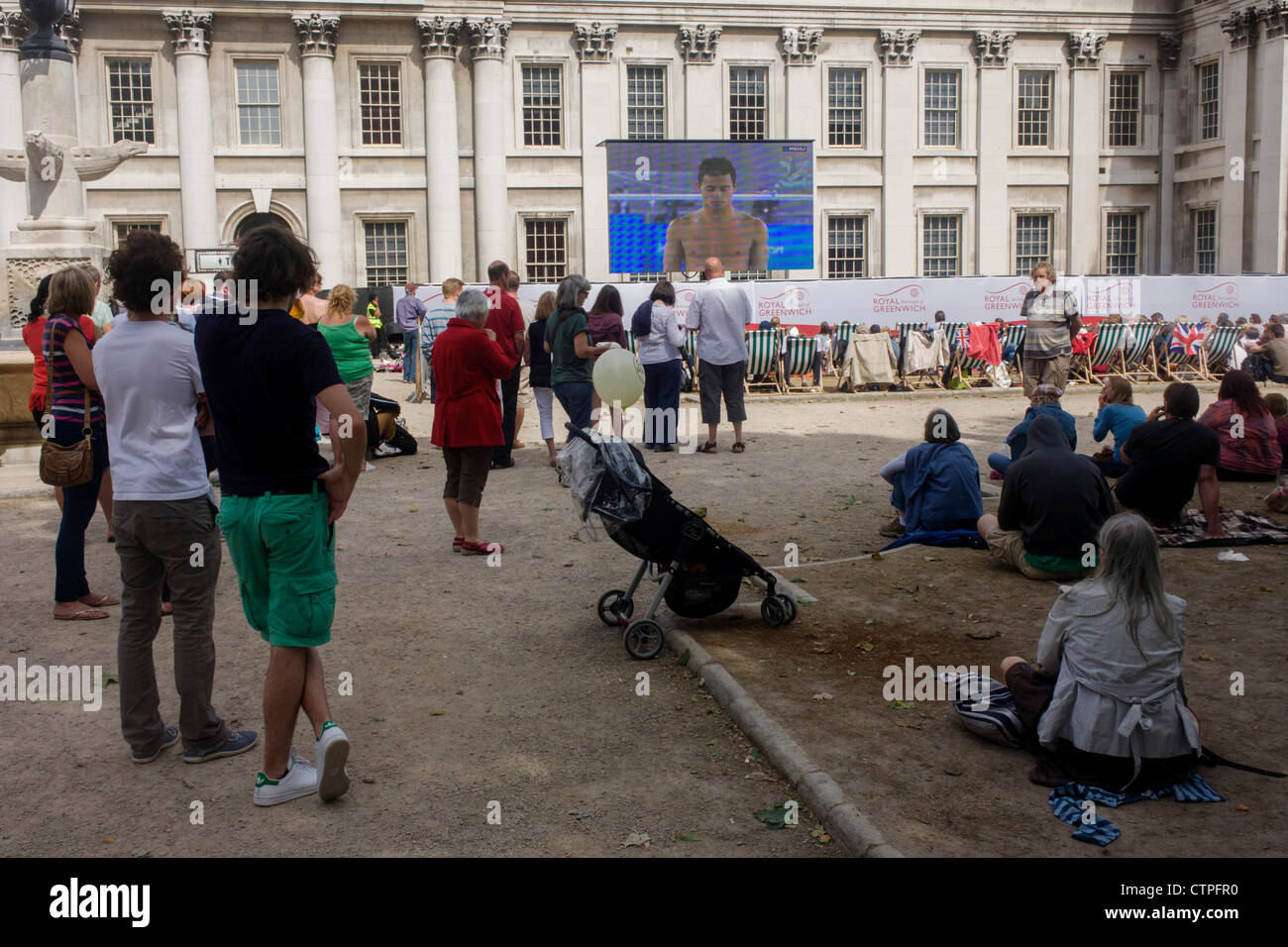 Spectators watch live TV coverage of the Diving event at the old Royal Naval College, Greenwich on day 4 of the London 2012 Olympic Games. Greenwich Park is hosting the Olympic Equestrian competitions, plus the combined running and shooting event of the Modern Pentathlon. The Old Royal Naval College is the architectural centrepiece of Maritime Greenwich, a World Heritage Site in Greenwich, London. Stock Photo