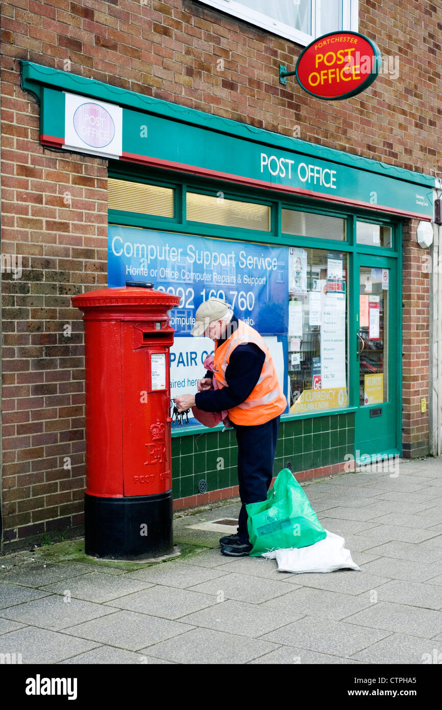 postman emptying post box outside of post office Stock Photo
