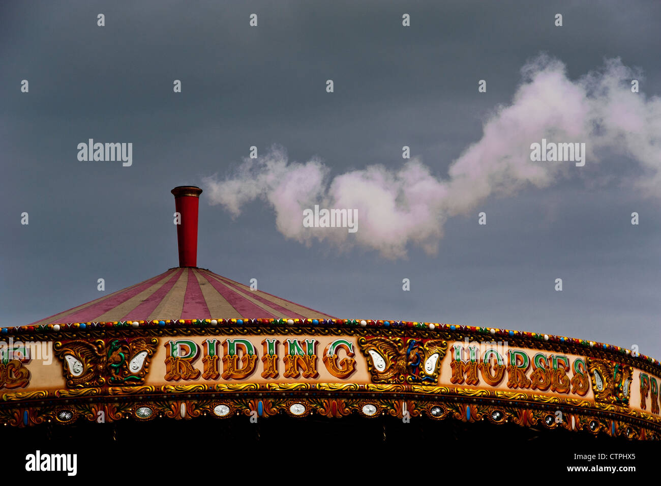 Steam or smoke escaping from the chimney on an old-fashioned steam-powered fairground merry-go-round. Stock Photo