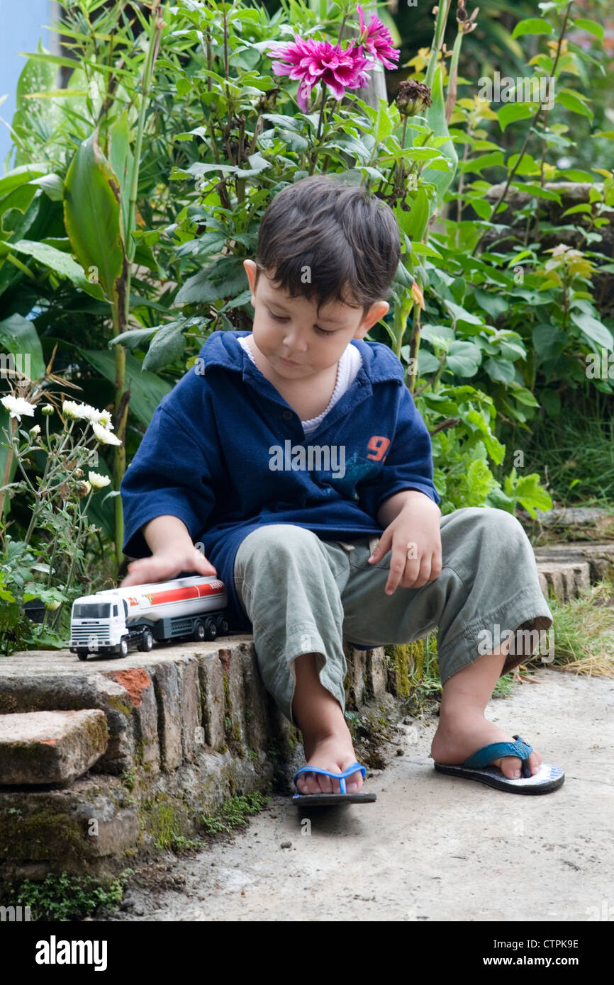 little boy playing with his toy cars in garden Stock Photo