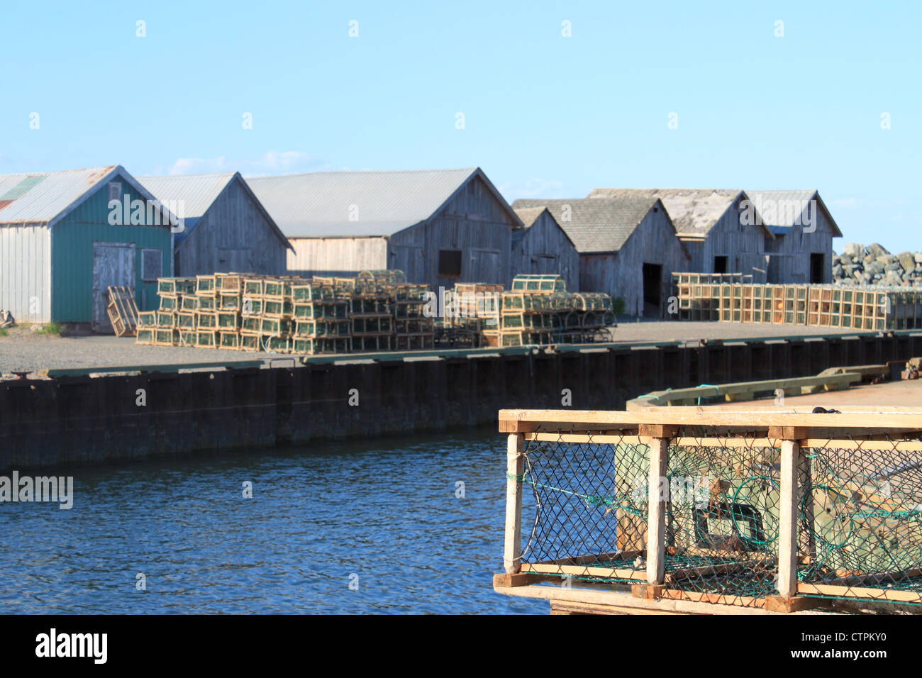 Lobster traps on shore with storage barns in the background, in Prince