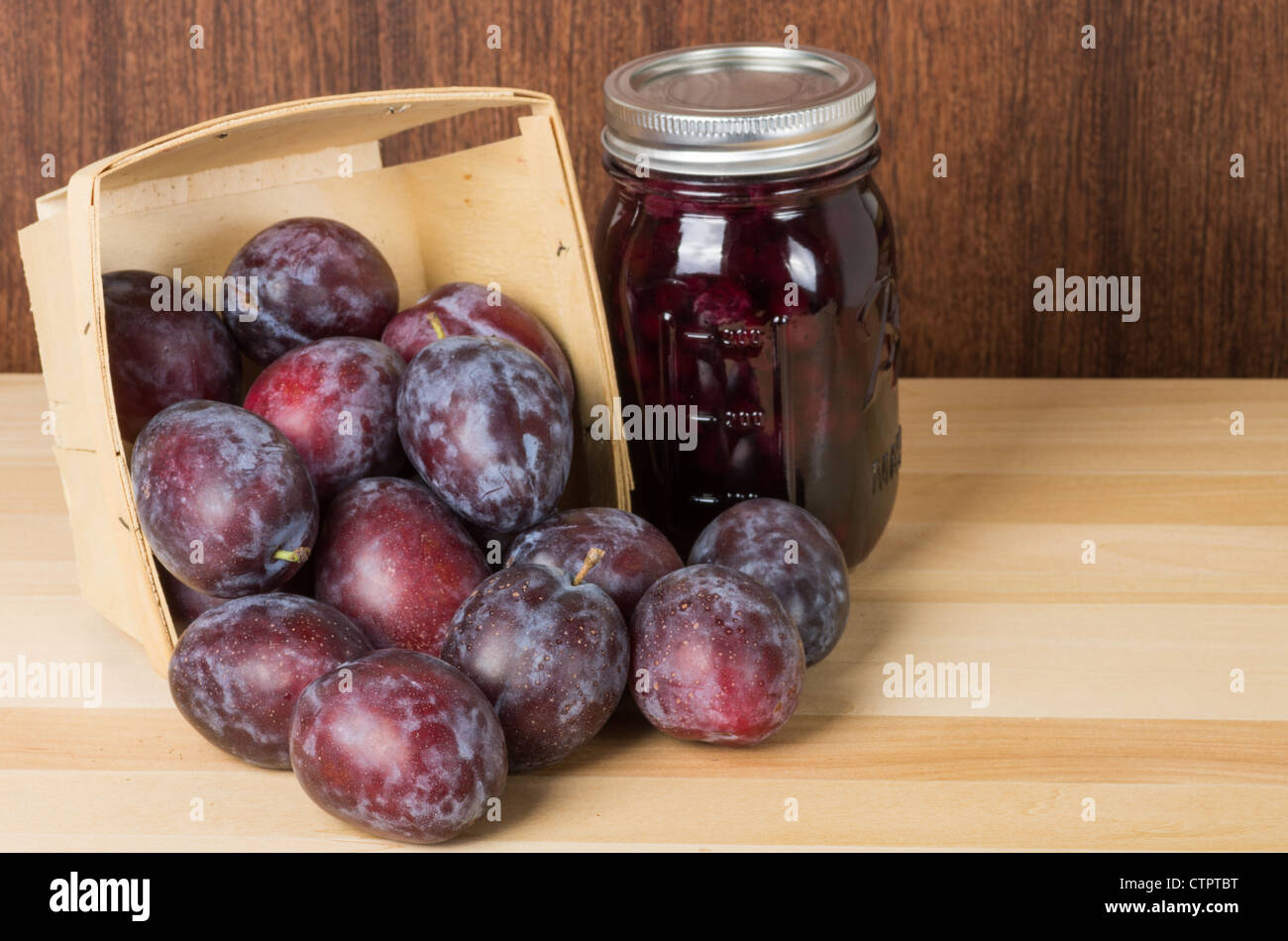 Prune plums in wooden container with a jar of plum jam or jelly Stock Photo
