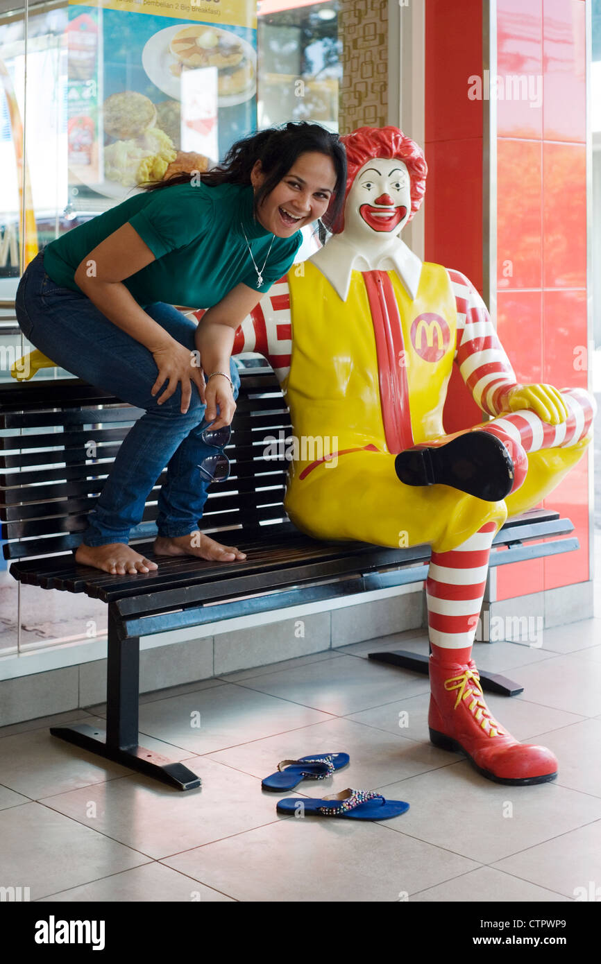 local woman laughing and posing with ronald mcdonald statue at mcdonalds restaurant malang java indonesia Stock Photo