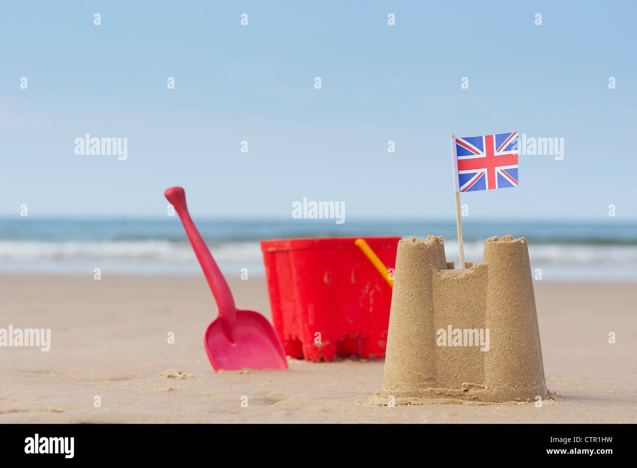 Union Jack flag in a sandcastle next to a childs bucket and spade on a beach. Wells next the sea. Norfolk, England Stock Photo