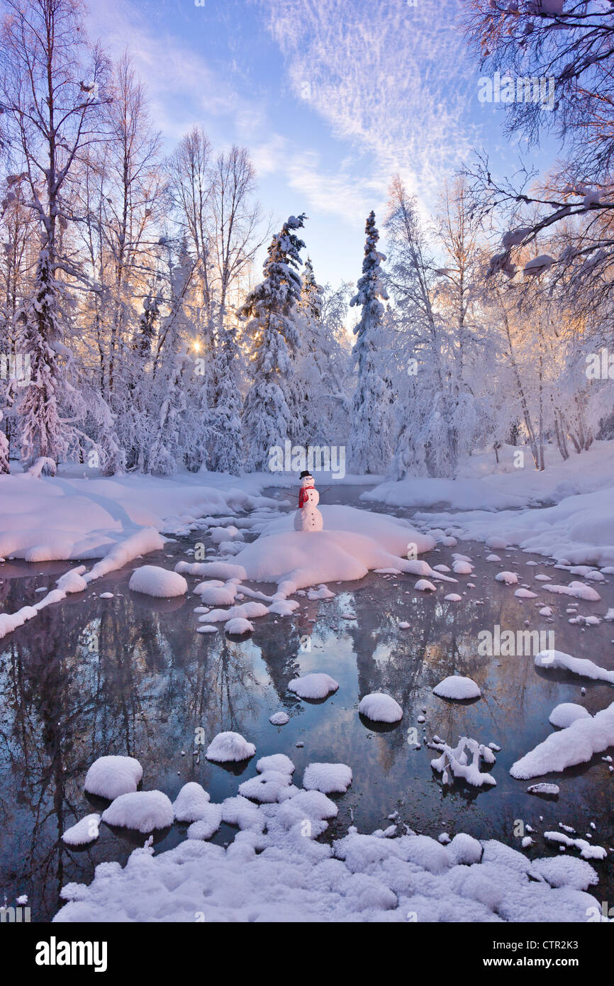 Snowman standing on small island in middle stream sunrays shining through fog hoar frosted trees in background Russian Jack Stock Photo