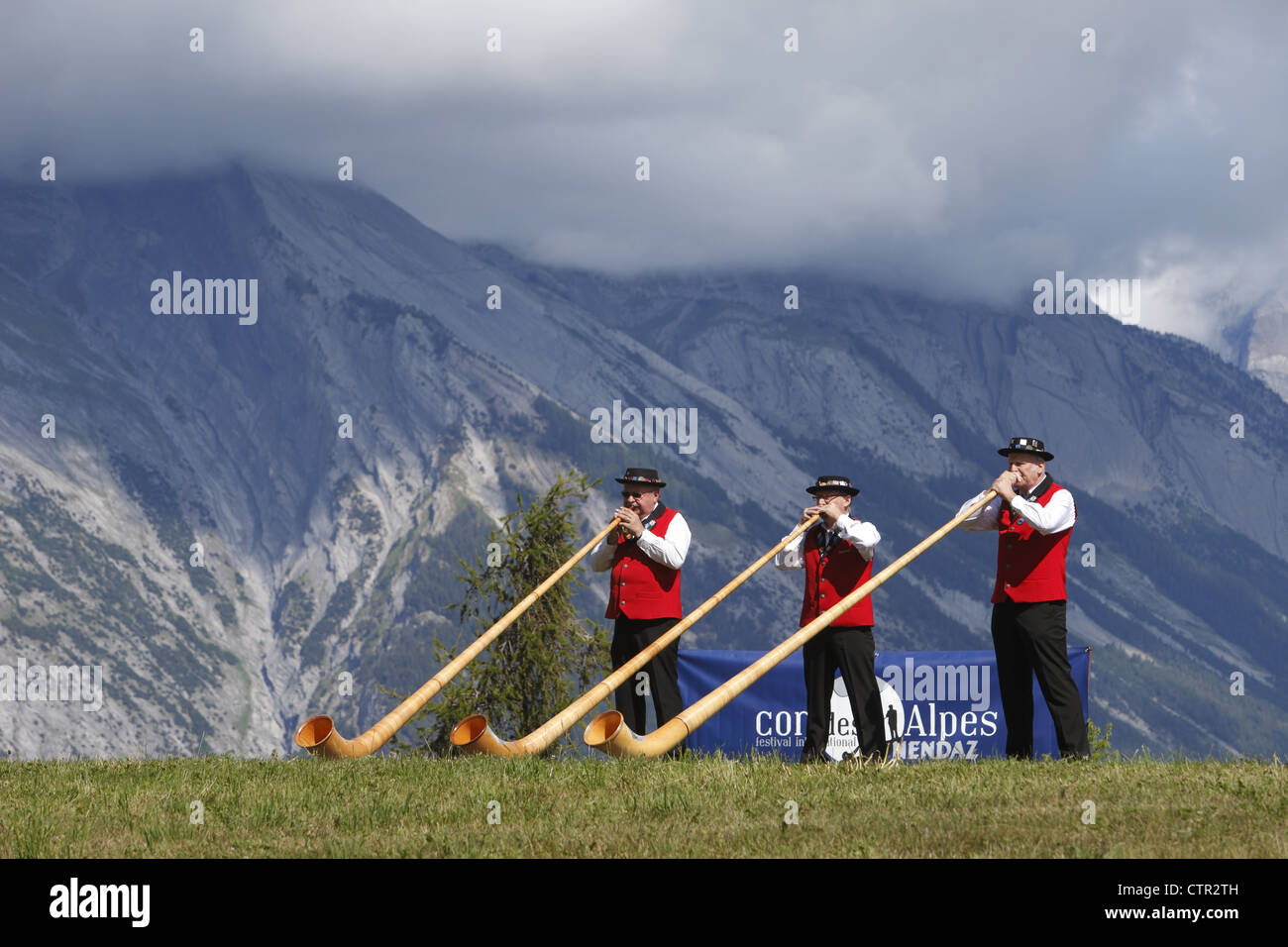 Alphorn players in traditional costume take part in the Cor des Alpes festival in the Alps of Nendaz, Valais, Switzerland Stock Photo