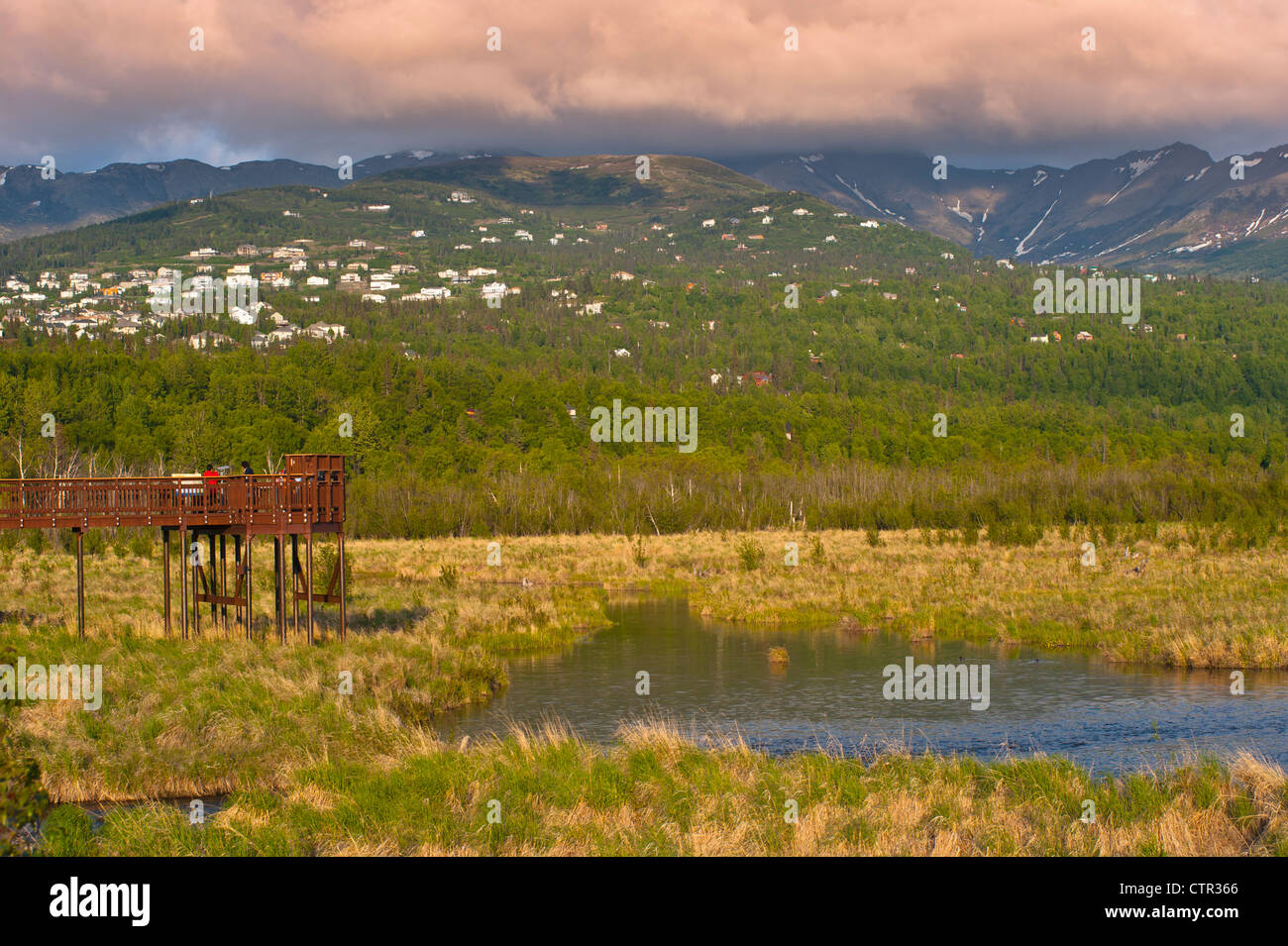 Visitors enjoy view boardwalk at Potter Marsh Anchorage hillside in background Southcentral Alaska Spring Stock Photo
