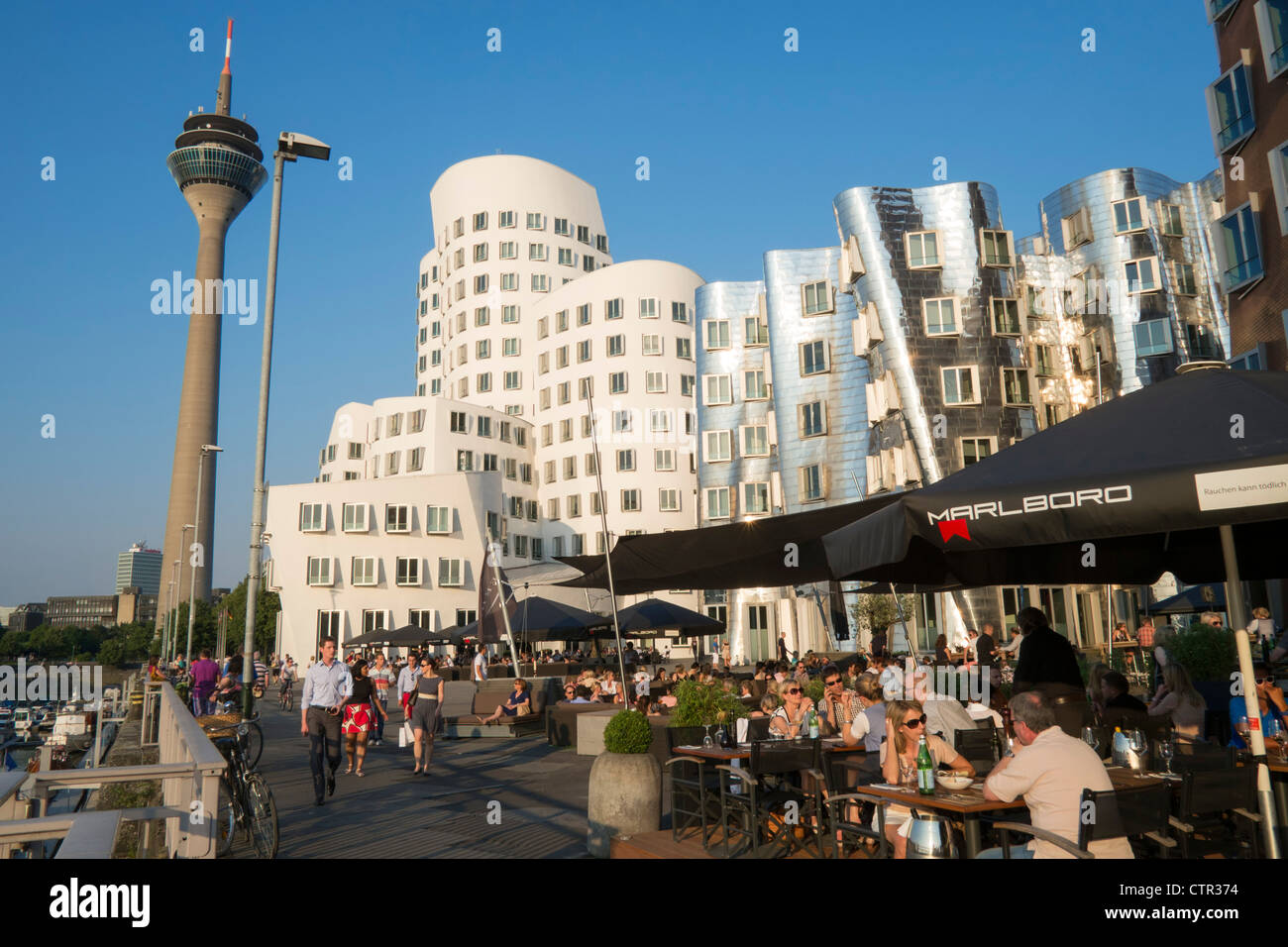 Busy bars and restaurant  in evening at Neuer Zollhof buildings designed by Frank Gehry in Medianhafen in Dusseldorf Germany Stock Photo