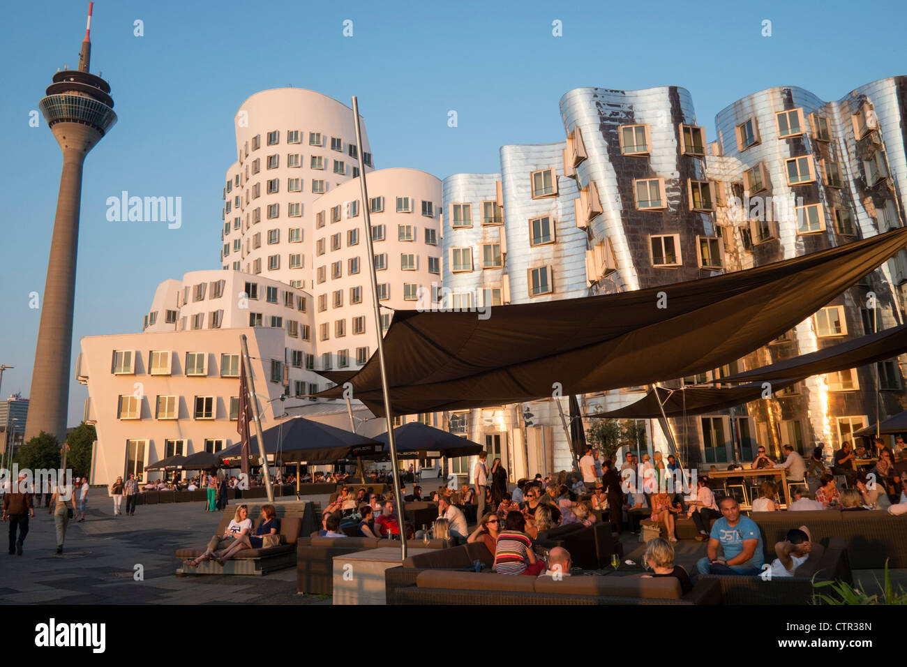 Busy bars in evening at Neuer Zollhof buildings designed by Frank Gehry in Medianhafen in Dusseldorf Germany Stock Photo