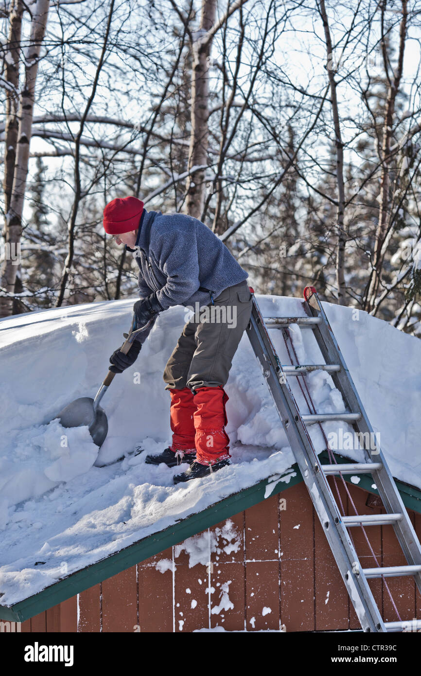 Man shovels snow from the roof of shed in Anchorage during a record