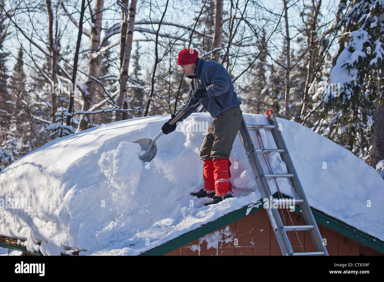 Man shovels snow from the roof of shed in Anchorage during a record