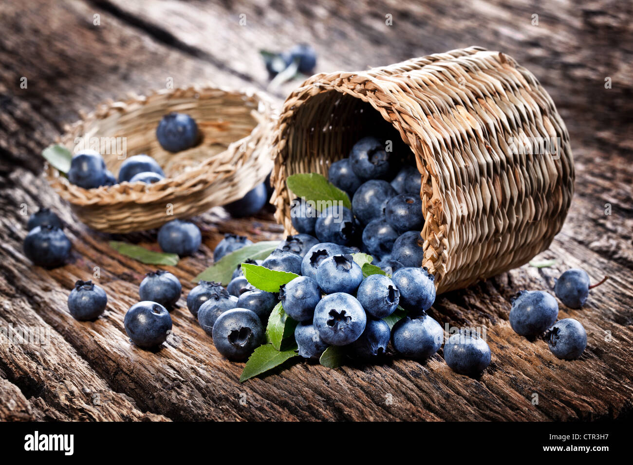 Blueberries have dropped from the basket on an old wooden table. Stock Photo