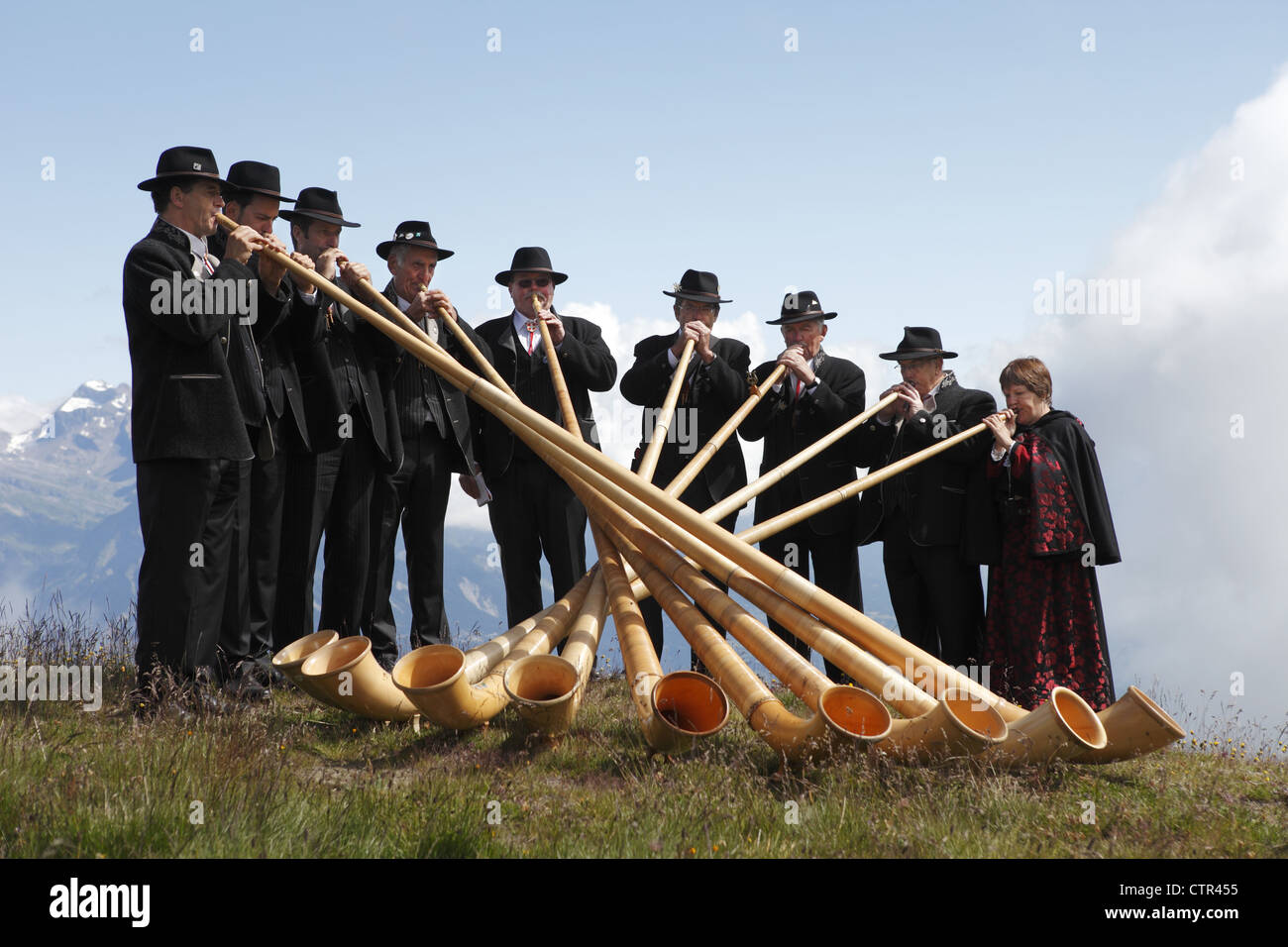 Alphorn players in traditional costume take part in the Cor des Alpes festival in the Alps of Nendaz, Valais, Switzerland Stock Photo