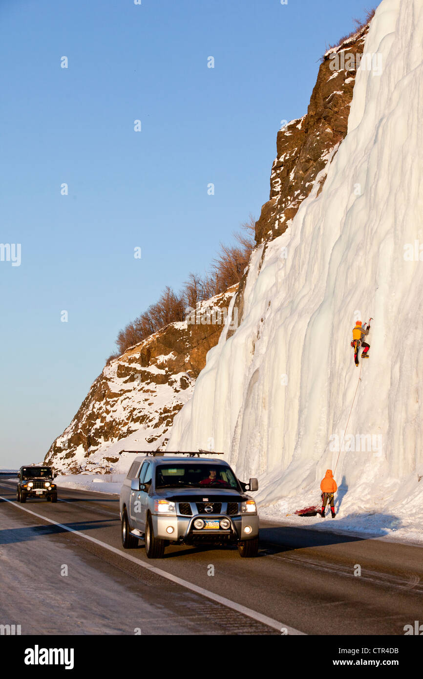 Ice climbers on frozen waterfall next to Seward Highway as traffic passes, Southcentral Alaska, Winter Stock Photo