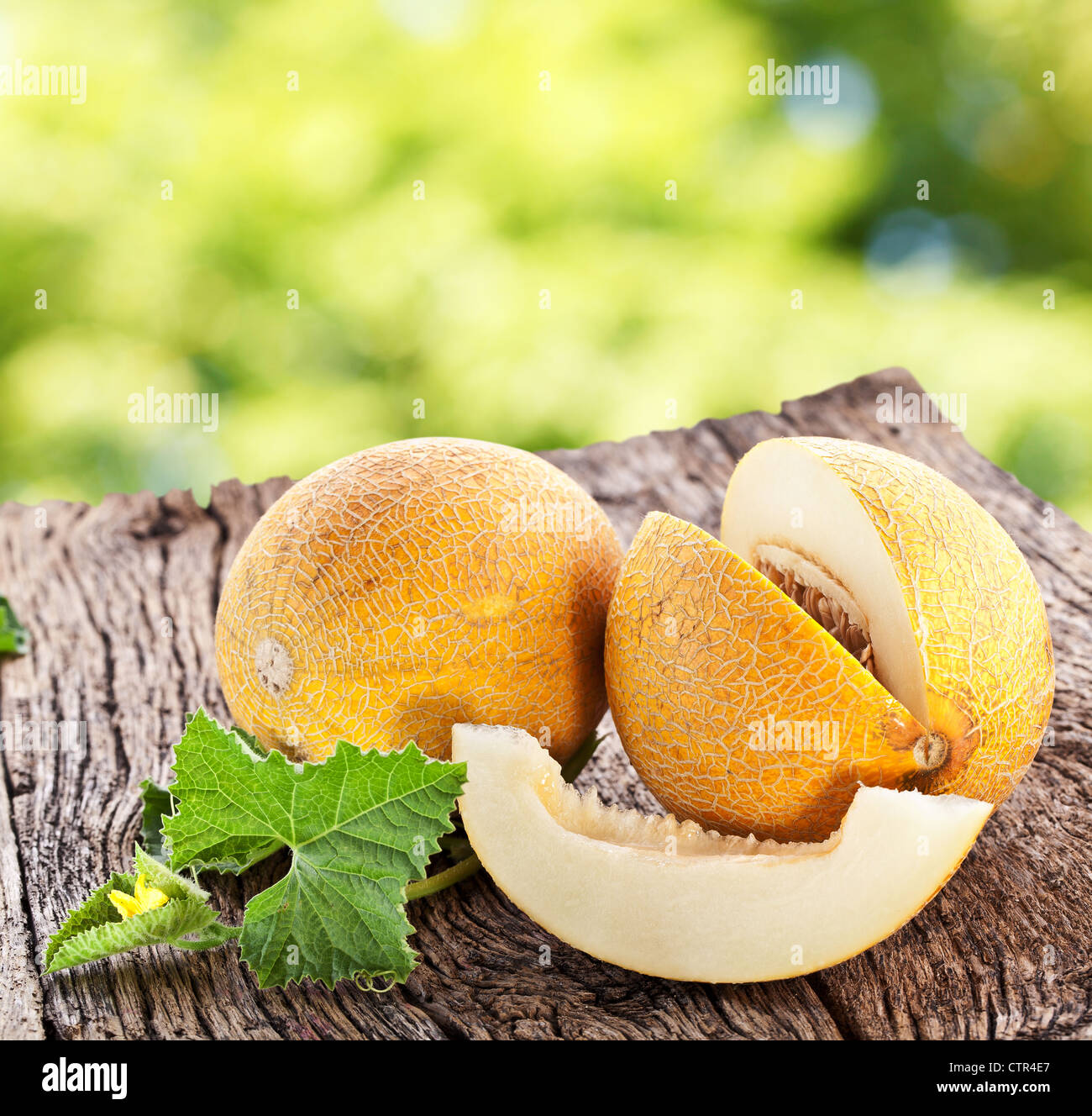 Melon with slices and leaves on a old wooden table. Stock Photo