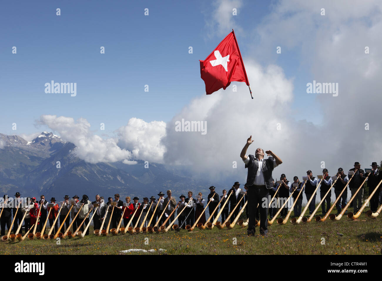 Flag throwers & alphorn players take part in the morceaux d’ensemble, in Cor des Alpes festival of Nendaz, Valais, Switzerland Stock Photo